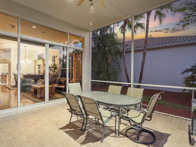 sunroom with ceiling fan with notable chandelier