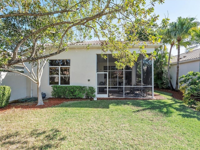 back of property with a lawn and a sunroom