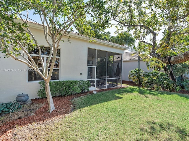 rear view of property featuring a lawn and a sunroom