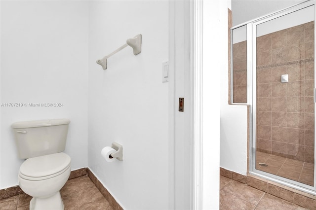 bathroom featuring tile patterned floors, a shower with door, and toilet