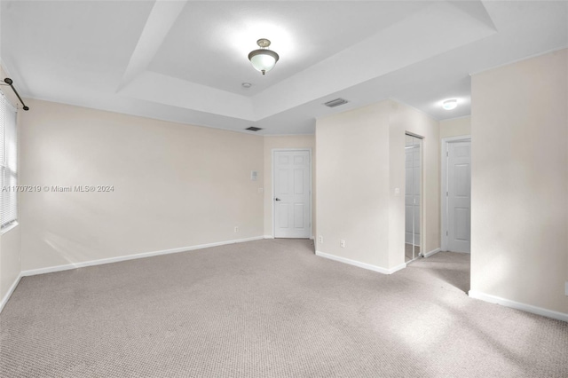 carpeted spare room featuring a tray ceiling