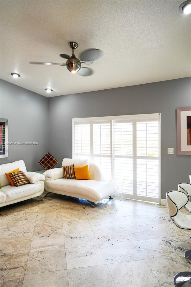 living area featuring ceiling fan, plenty of natural light, and a textured ceiling