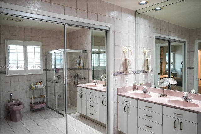 bathroom with tile patterned flooring, a bidet, vanity, a shower with shower door, and tile walls