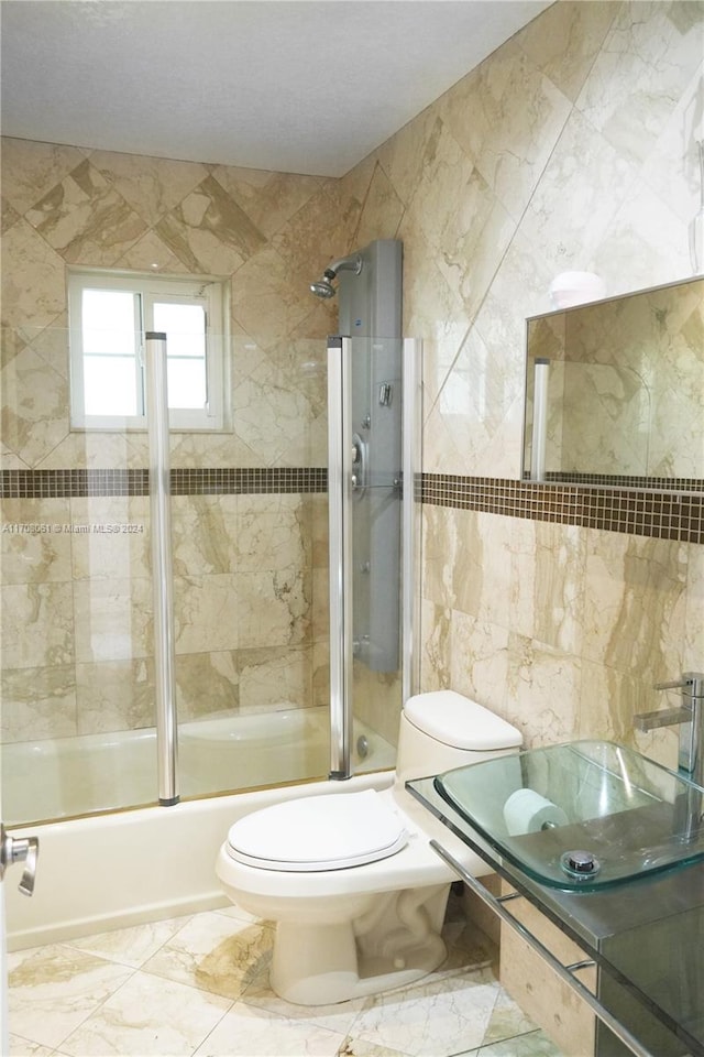 full bathroom featuring sink, toilet, tile walls, and enclosed tub / shower combo