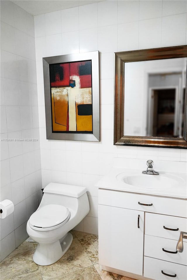 bathroom featuring tile patterned floors, vanity, tile walls, and toilet