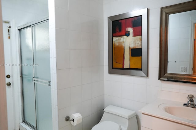 bathroom with vanity, an enclosed shower, tile walls, and toilet