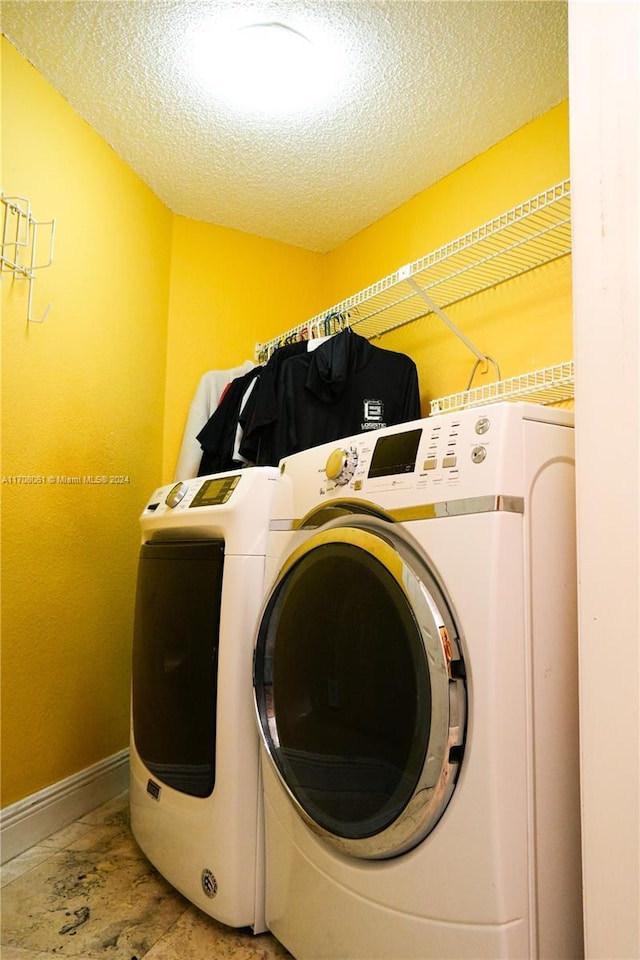 laundry area with a textured ceiling and washing machine and clothes dryer