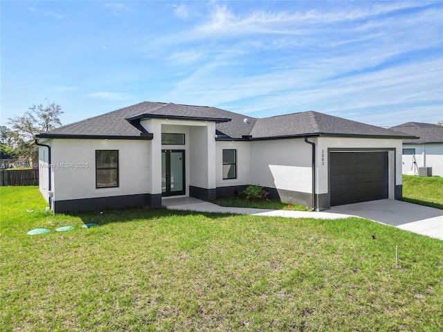 prairie-style home with a garage, a shingled roof, concrete driveway, stucco siding, and a front lawn