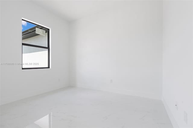 empty room featuring marble finish floor and baseboards