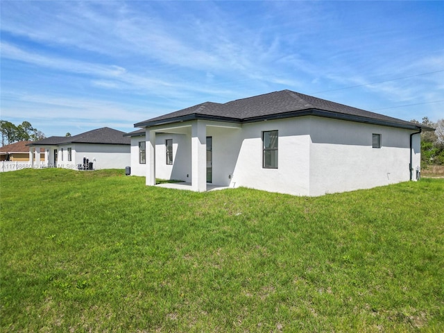 back of property featuring a lawn and stucco siding