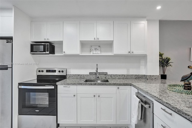 kitchen featuring appliances with stainless steel finishes, light stone counters, white cabinetry, and sink