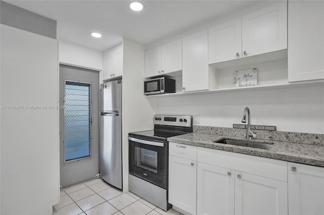 kitchen featuring sink, light tile patterned floors, light stone countertops, appliances with stainless steel finishes, and white cabinetry