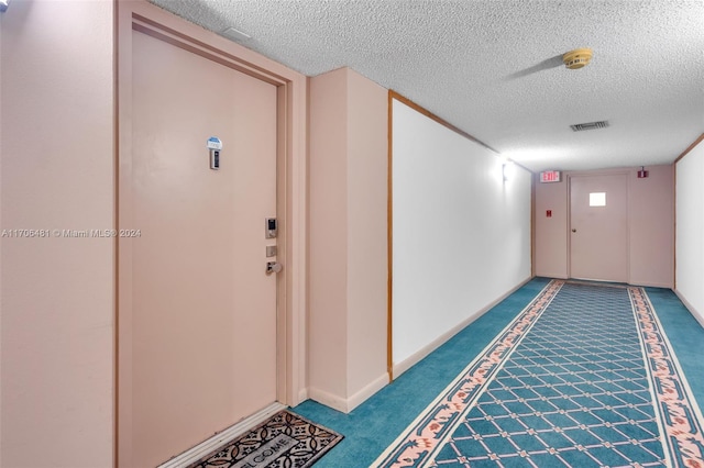 hall with carpet flooring and a textured ceiling