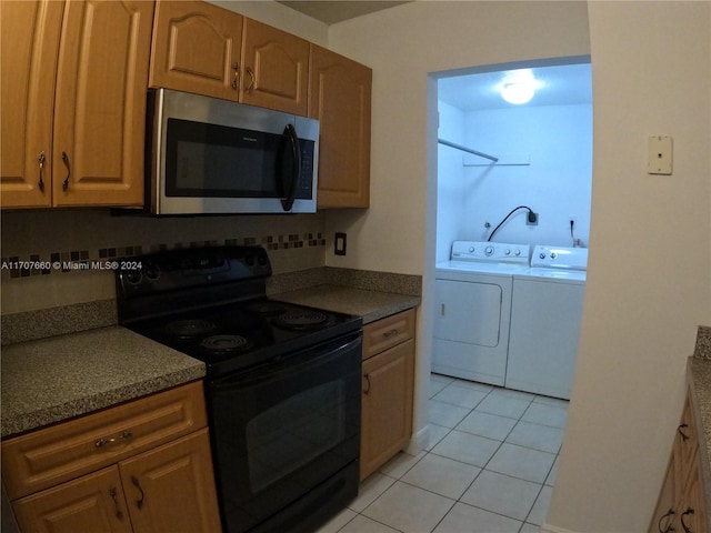 kitchen featuring black electric range oven, light tile patterned flooring, independent washer and dryer, and tasteful backsplash