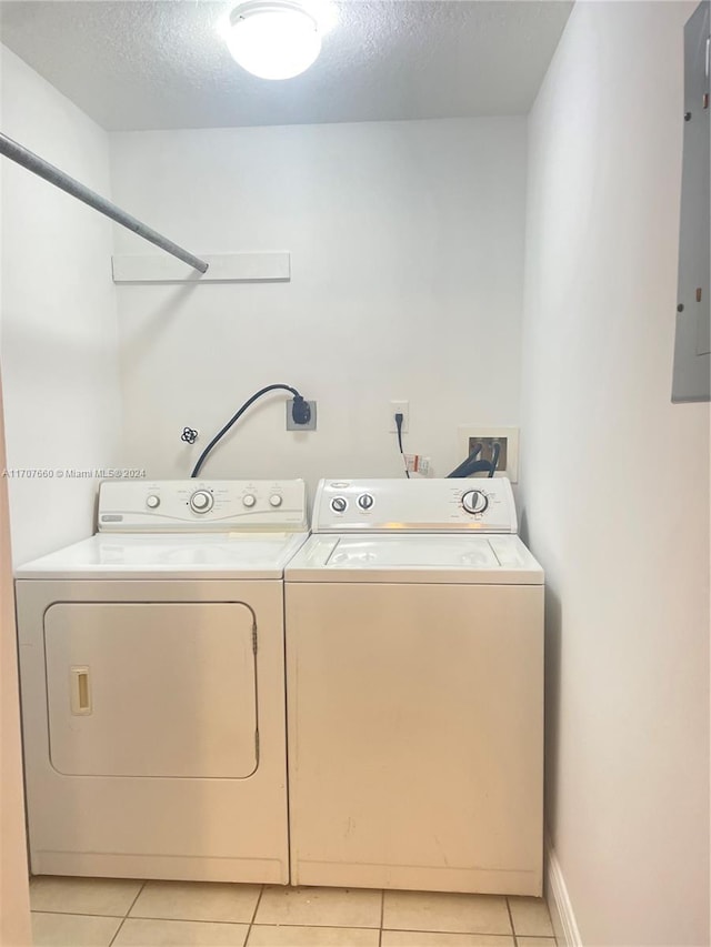 laundry room featuring separate washer and dryer, a textured ceiling, and light tile patterned floors