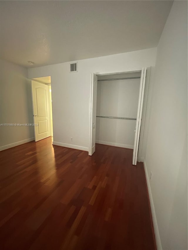 unfurnished bedroom featuring dark hardwood / wood-style flooring and a closet