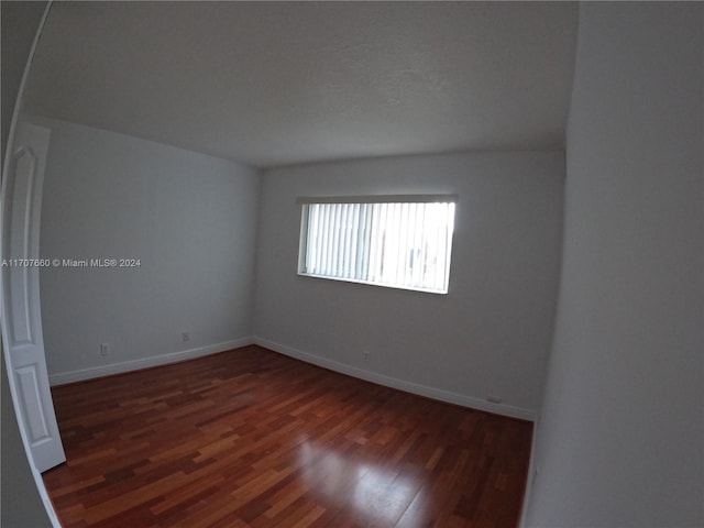 spare room featuring a textured ceiling and dark hardwood / wood-style flooring