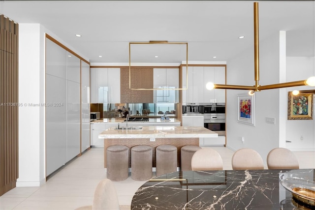 kitchen with a kitchen bar, light stone counters, white cabinets, and a kitchen island