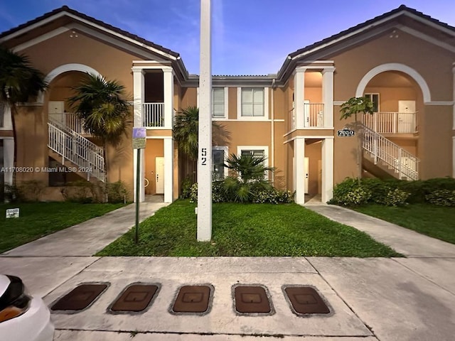 7050 NW 177th St Unit 107-11, Hialeah, FL 33015 - view of front of house with stairway, stucco siding, a tiled roof, and a front yard