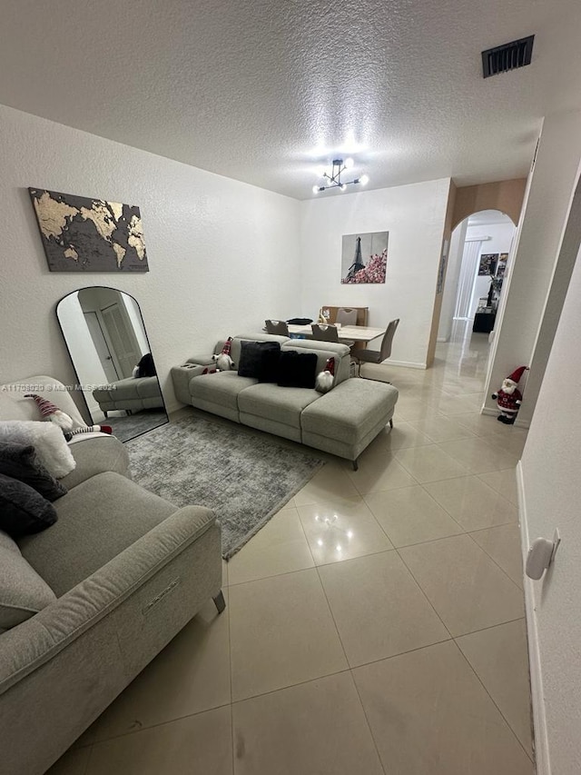 living room featuring a textured ceiling, a notable chandelier, and light tile patterned flooring