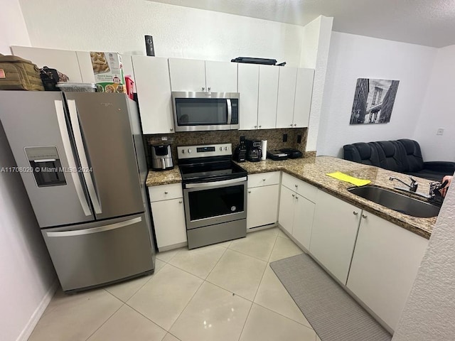 kitchen featuring white cabinets, sink, decorative backsplash, light tile patterned flooring, and stainless steel appliances