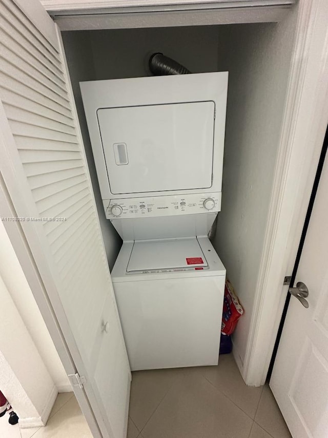 laundry room featuring stacked washing maching and dryer and light tile patterned floors