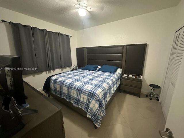 bedroom featuring a textured ceiling, a closet, ceiling fan, and light tile patterned flooring