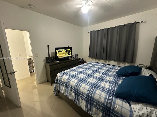 tiled bedroom with ceiling fan and a textured ceiling