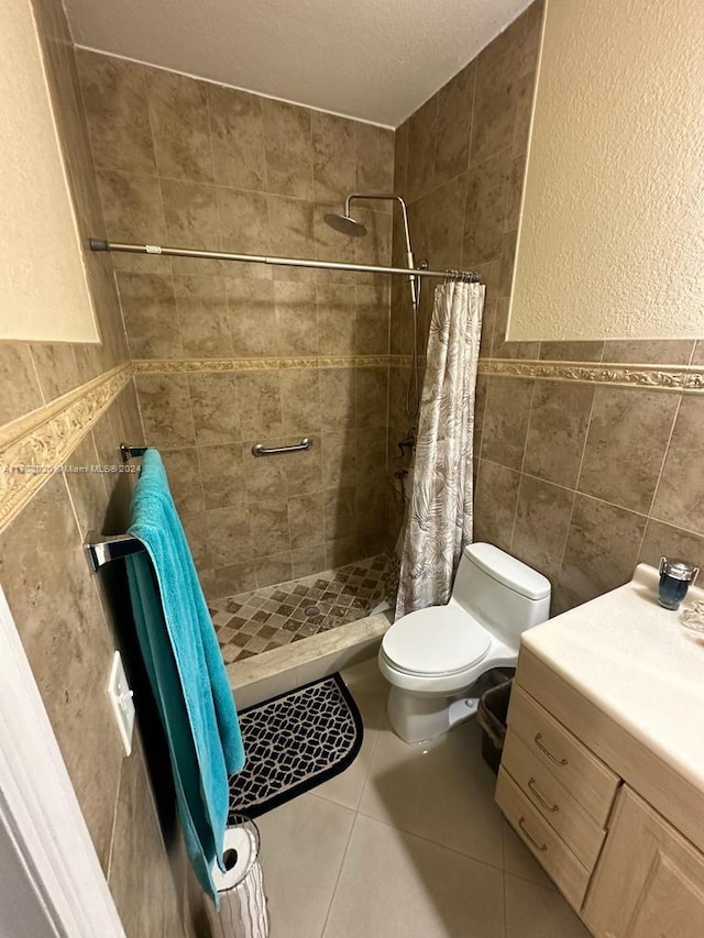 bathroom featuring walk in shower, vanity, toilet, and tile walls