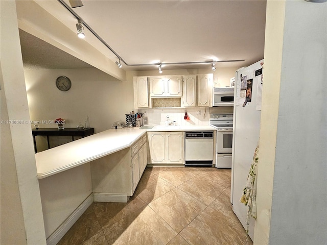 kitchen featuring sink, track lighting, kitchen peninsula, white appliances, and decorative backsplash