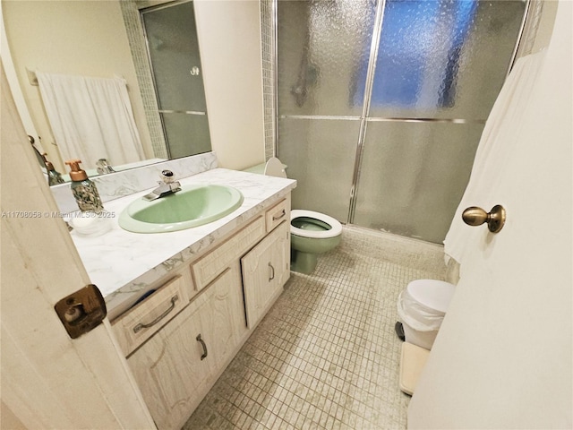 bathroom with tile patterned flooring, vanity, a shower with shower door, and toilet