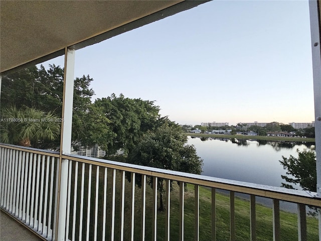 balcony at dusk featuring a water view