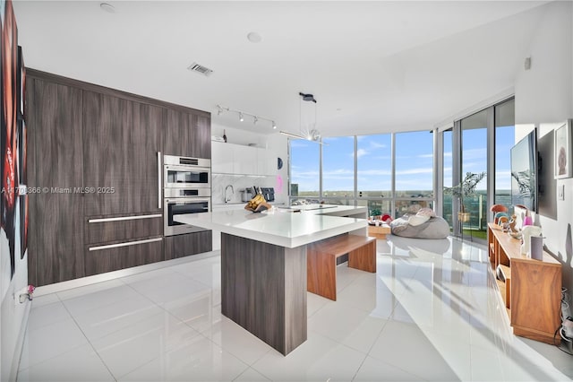 kitchen featuring a kitchen island, a kitchen breakfast bar, white cabinets, decorative light fixtures, and light tile patterned floors