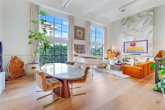 dining room with a towering ceiling, beamed ceiling, and light hardwood / wood-style floors