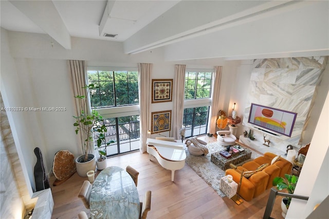 living area with high vaulted ceiling, beamed ceiling, wood finished floors, and visible vents