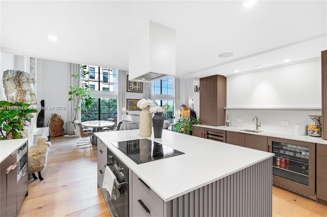 101 N Clematis St Unit 308, West Palm Beach, FL 33401 - kitchen featuring black appliances, wine cooler, light countertops, light wood-type flooring, and modern cabinets