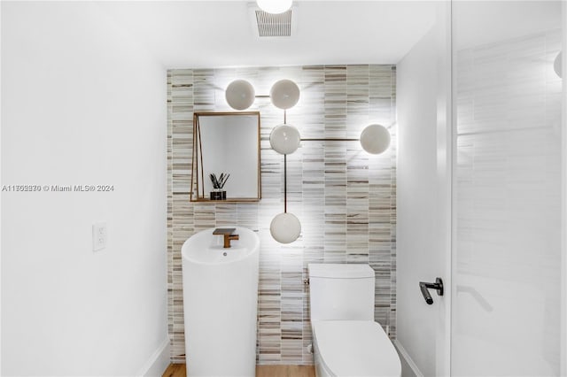 bathroom featuring tile walls and toilet