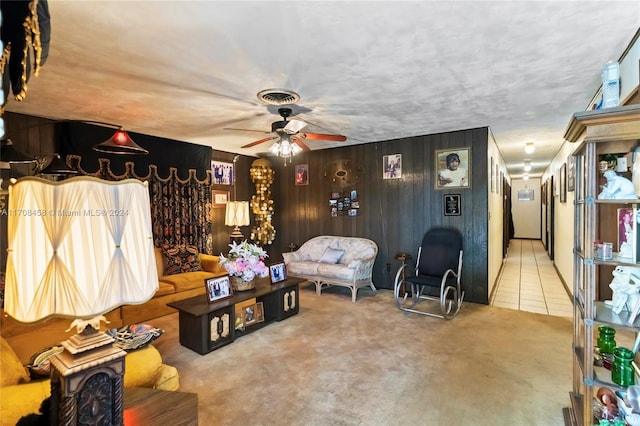 living room featuring tile patterned floors, ceiling fan, and wood walls