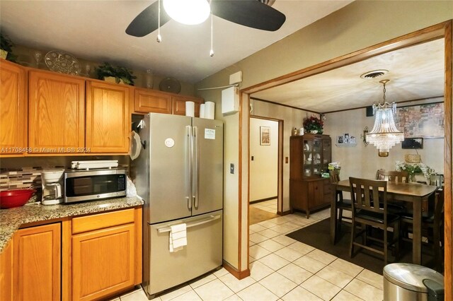 kitchen featuring pendant lighting, stainless steel appliances, light stone counters, and light tile patterned flooring