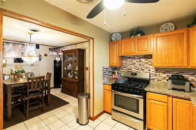 kitchen with light stone countertops, tasteful backsplash, light tile patterned floors, decorative light fixtures, and stainless steel range with gas cooktop