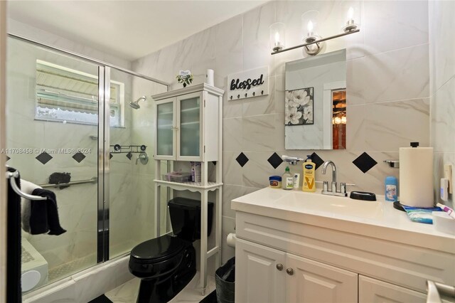 bathroom with toilet, decorative backsplash, a shower with door, vanity, and tile walls