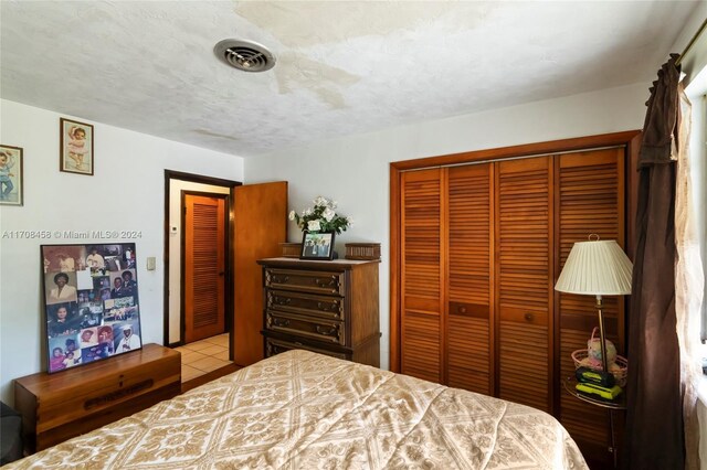 tiled bedroom with a textured ceiling and a closet