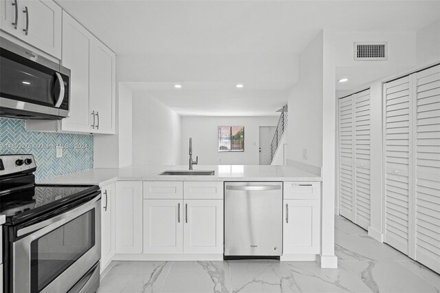 kitchen with white cabinets, sink, kitchen peninsula, and stainless steel appliances