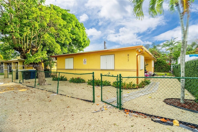 view of home's exterior with stucco siding, fence private yard, and a gate