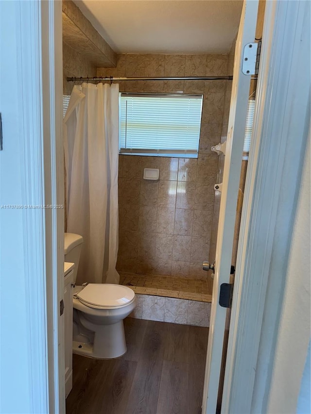 full bathroom with wood finished floors, toilet, and a stall shower