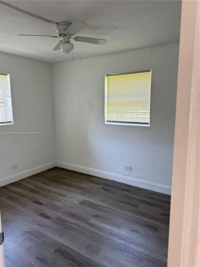 empty room with dark wood-style floors, baseboards, and a ceiling fan