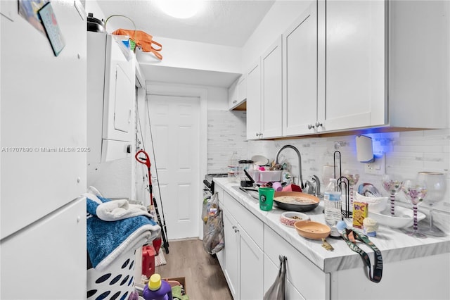 kitchen with white cabinetry, backsplash, light countertops, and light wood-style flooring