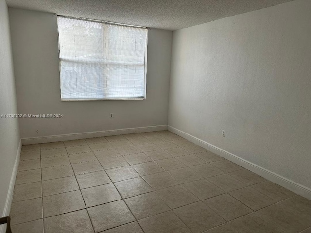 tiled spare room with a textured ceiling