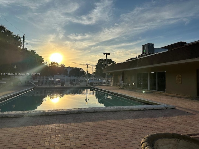 pool at dusk featuring central AC unit and a patio area