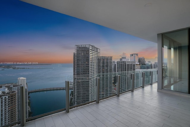 balcony at dusk featuring a water view